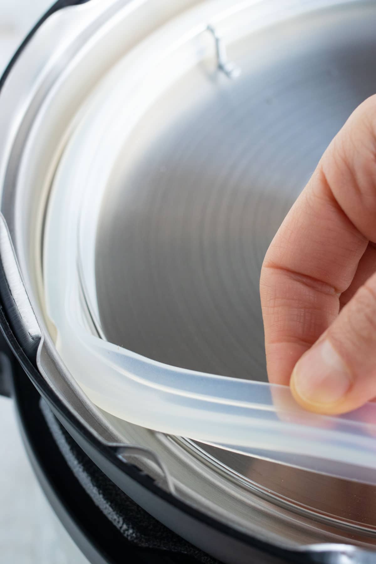 A hand removing and placing the silicone ring around the lid of an Instant Pot.