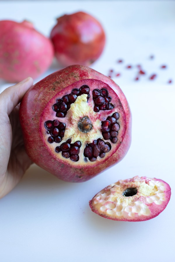 A pomegranate is cut open on the stem side.