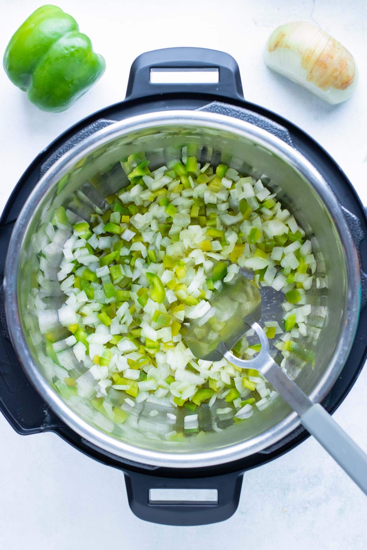 Green peppers and onions are sautéed in the instant pot.