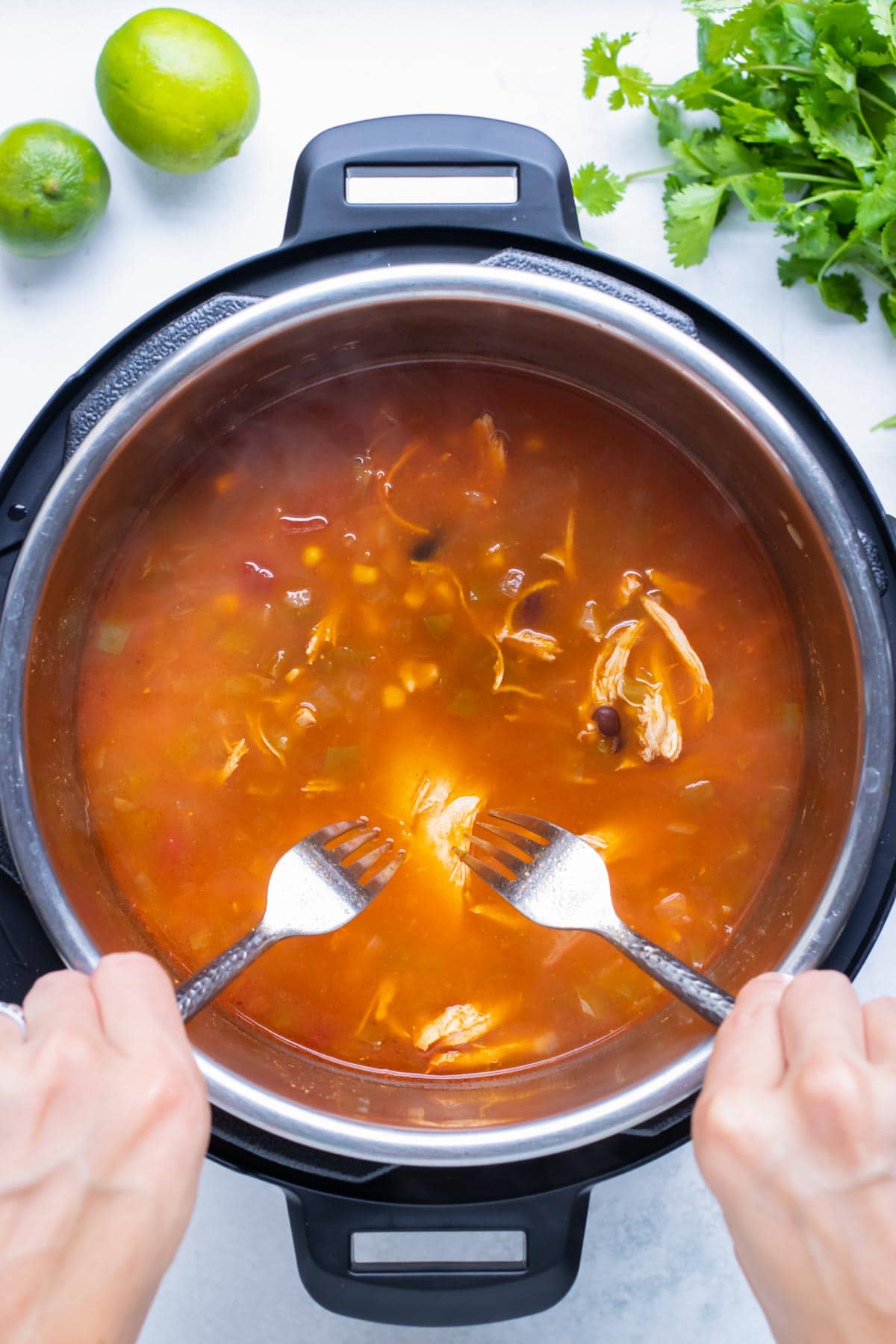 Chicken is shredded with two forks in the instant pot.