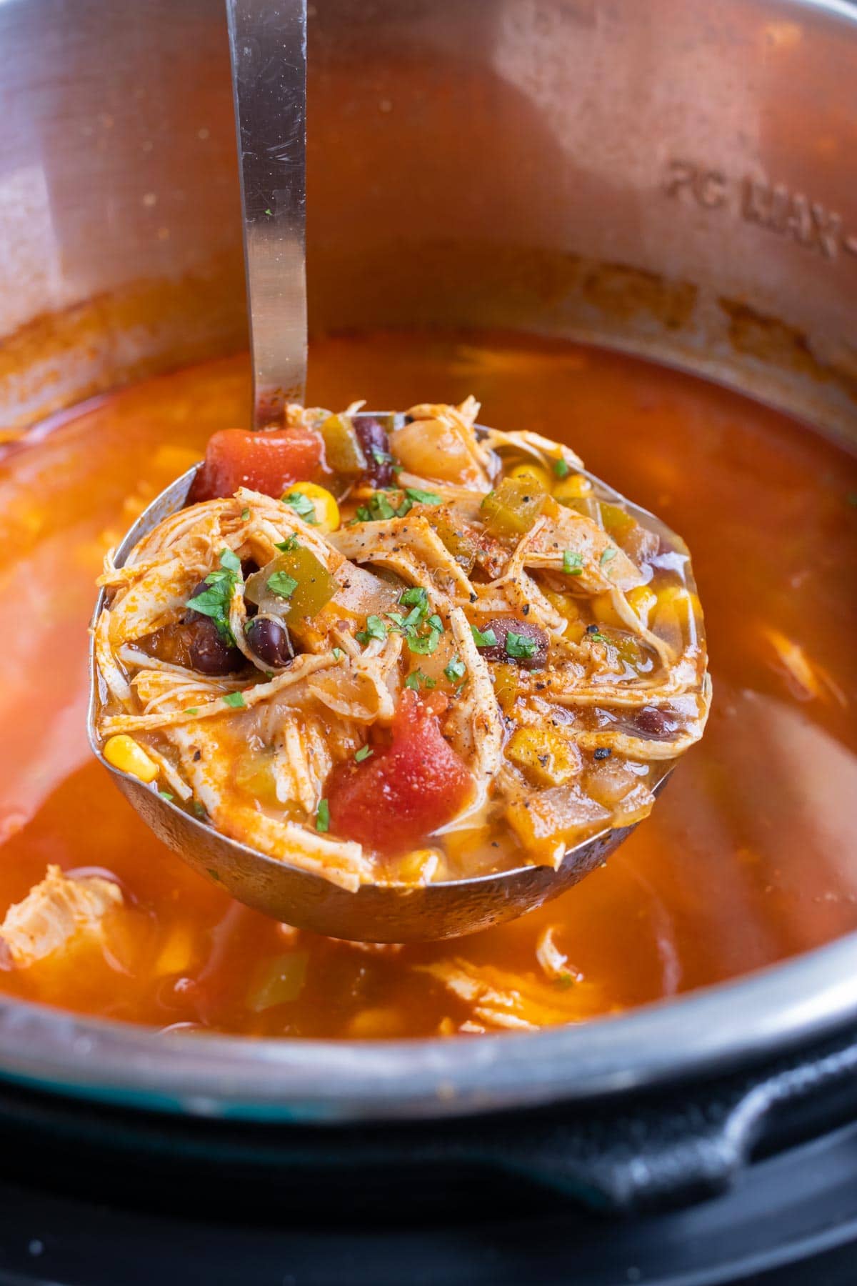 A 6-quart Instant Pot pressure cooker with chicken tortilla soup being ladled out.