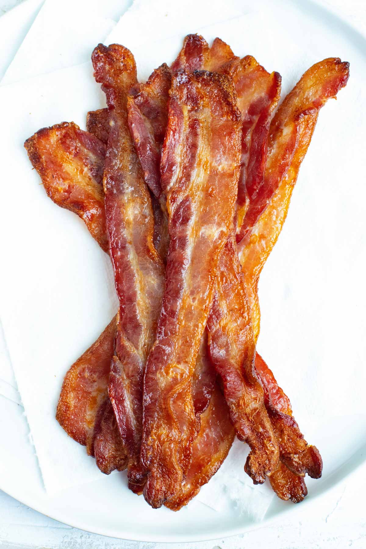 Bacon strips that have been cooked in the oven draining on paper towels.