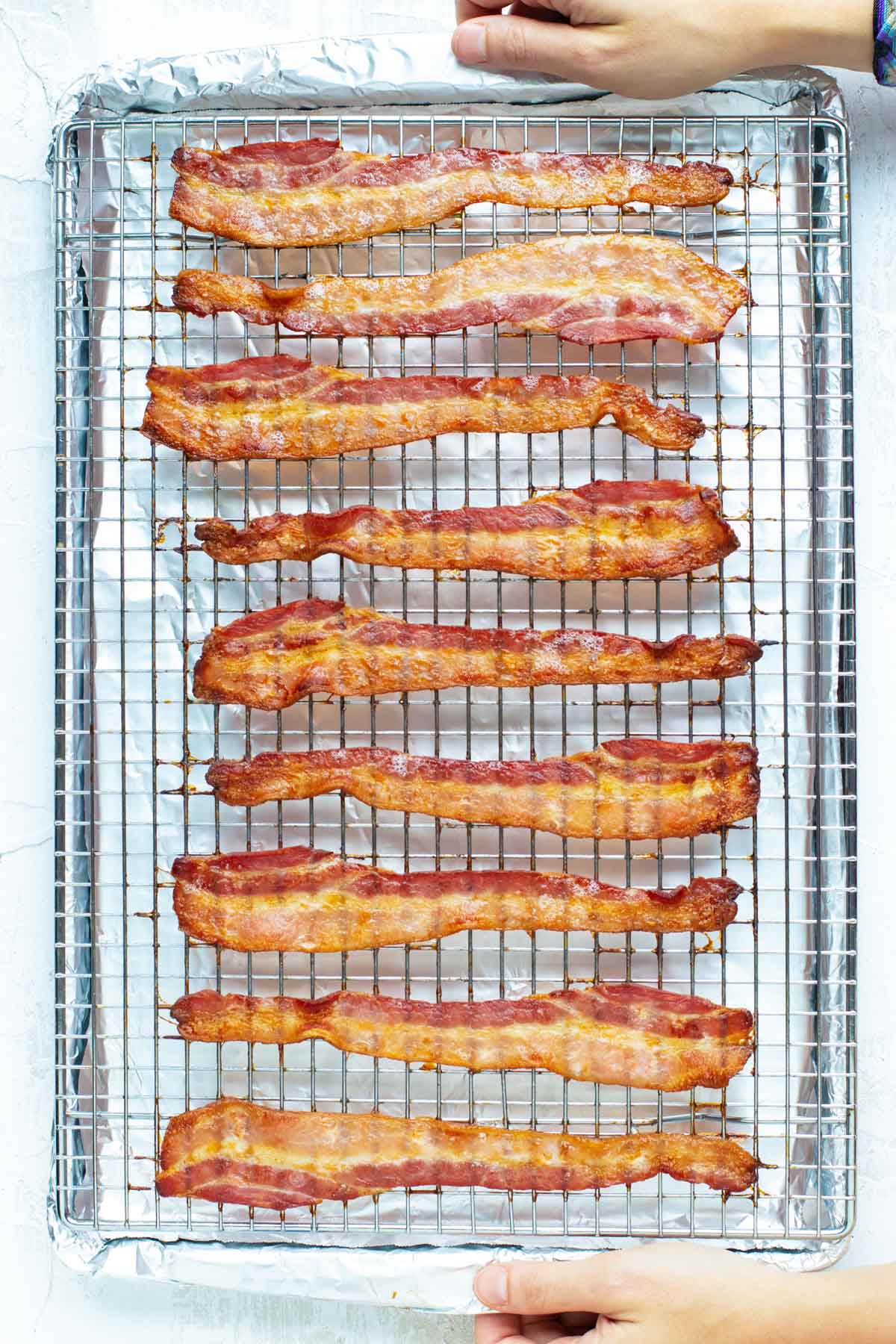 A baking sheet with a wire rack and bacon that has been cooked in the oven.