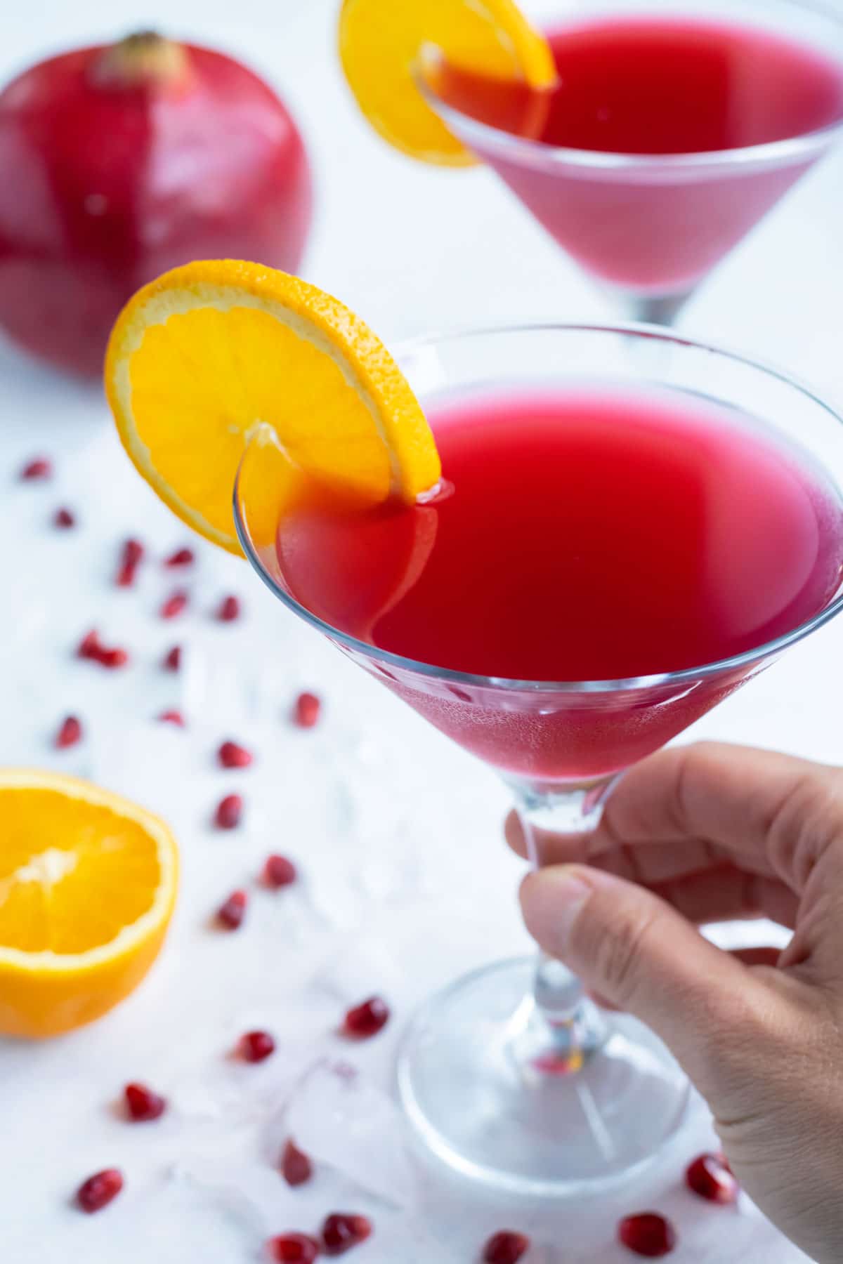 A hand is shown holding a martini glass.