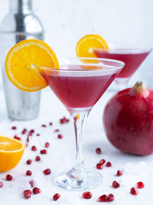 Two pomegranate martinis are shown on the counter for a holiday drink.