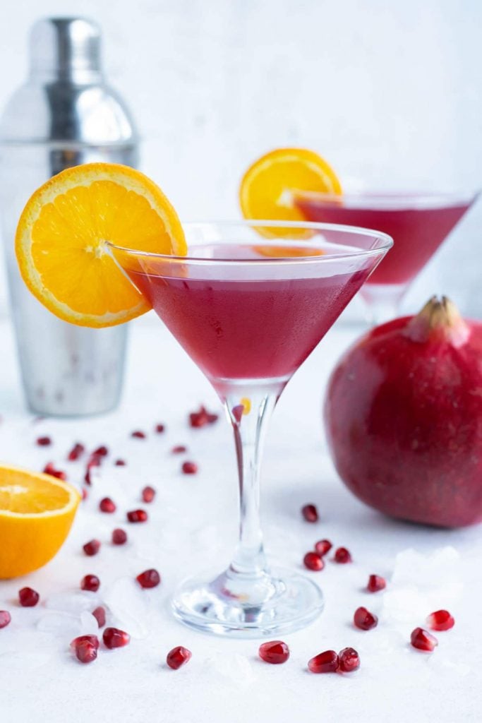 Two pomegranate martinis are shown on the counter for a holiday drink.
