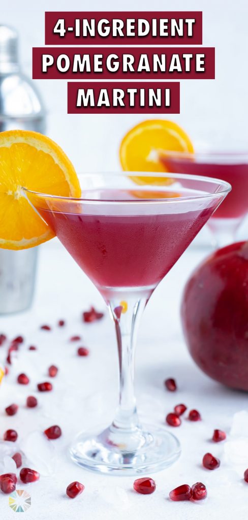 A glass of pomegranate martini is garnished with an orange slice.