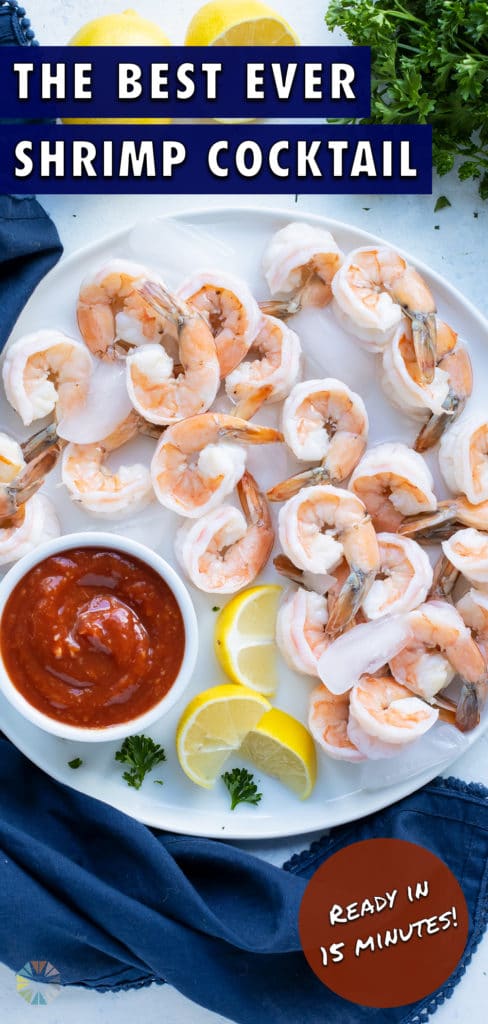 Shrimp is served on a plate with a cup of cocktail sauce.
