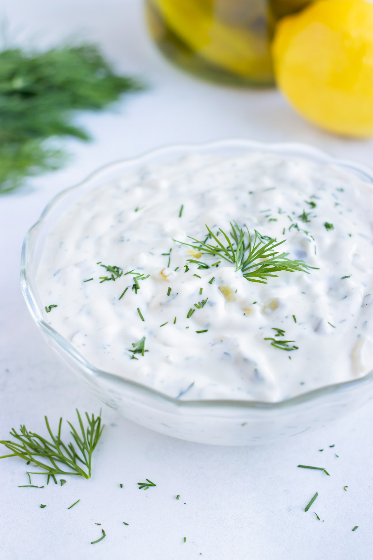 Fresh dill is placed on top of homemade tartar sauce recipe.