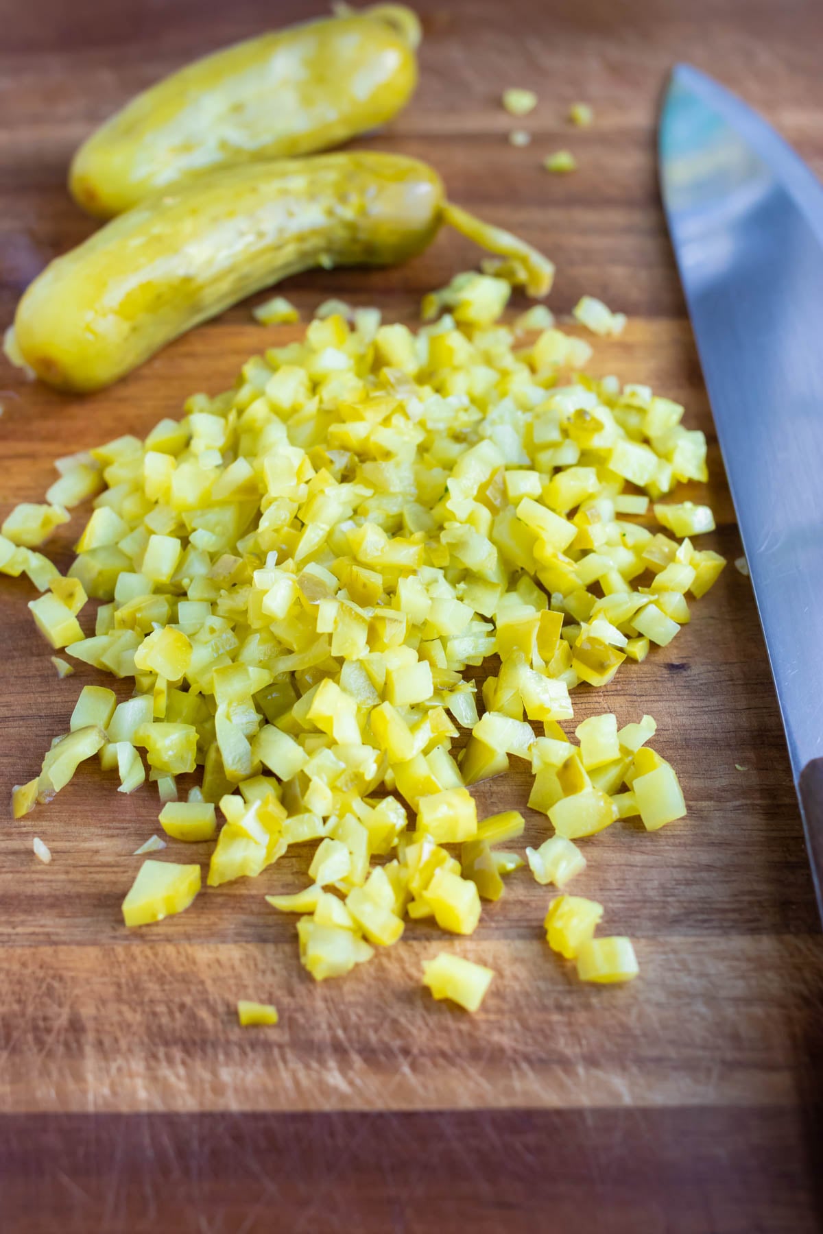 Dill pickles diced small on a cutting board for tartar sauce from scratch.