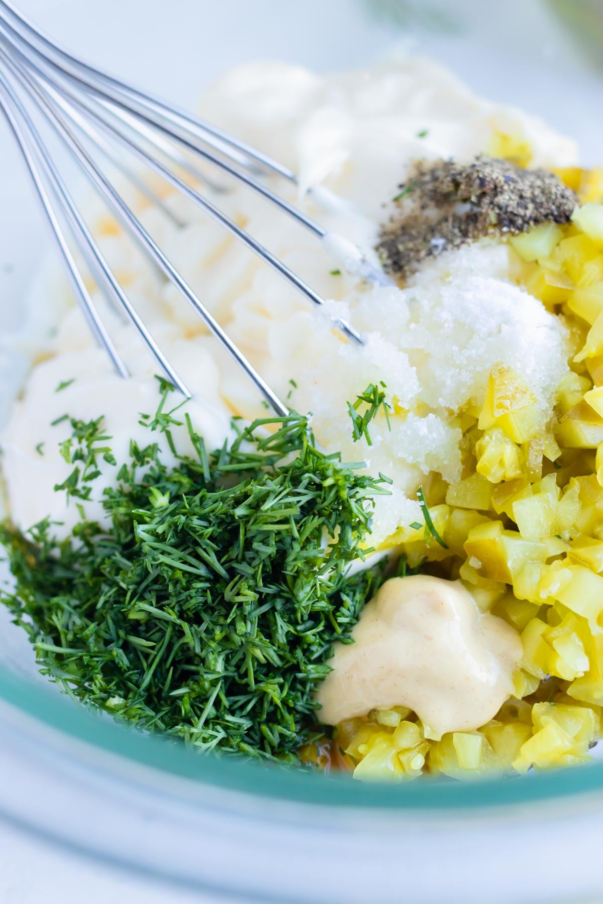 Diced pickles, fresh dill, and mayonnaise in a bowl before the sauce is stirred.