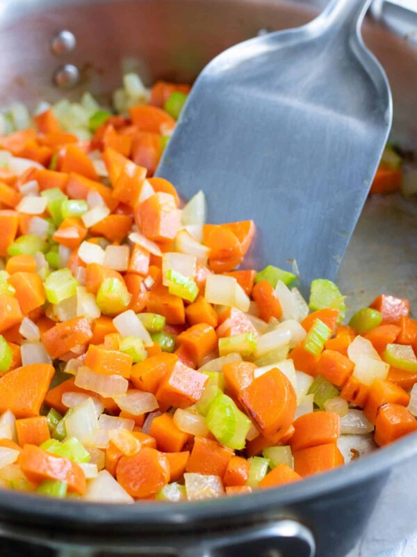 Carrots, celery, and onion are sautéed on the stove.