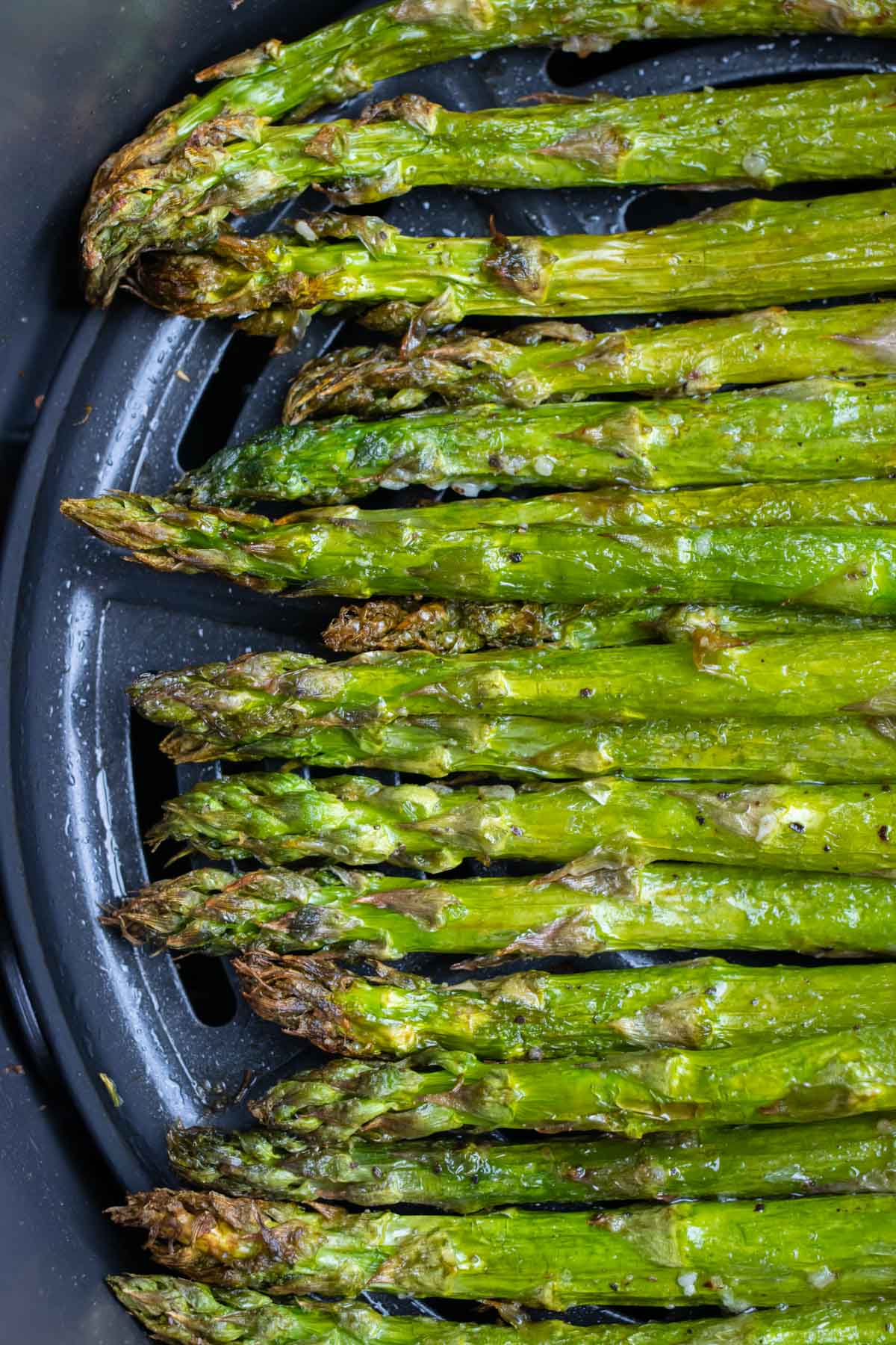 Air Fryer Asparagus is in the basket with salt and black pepper.