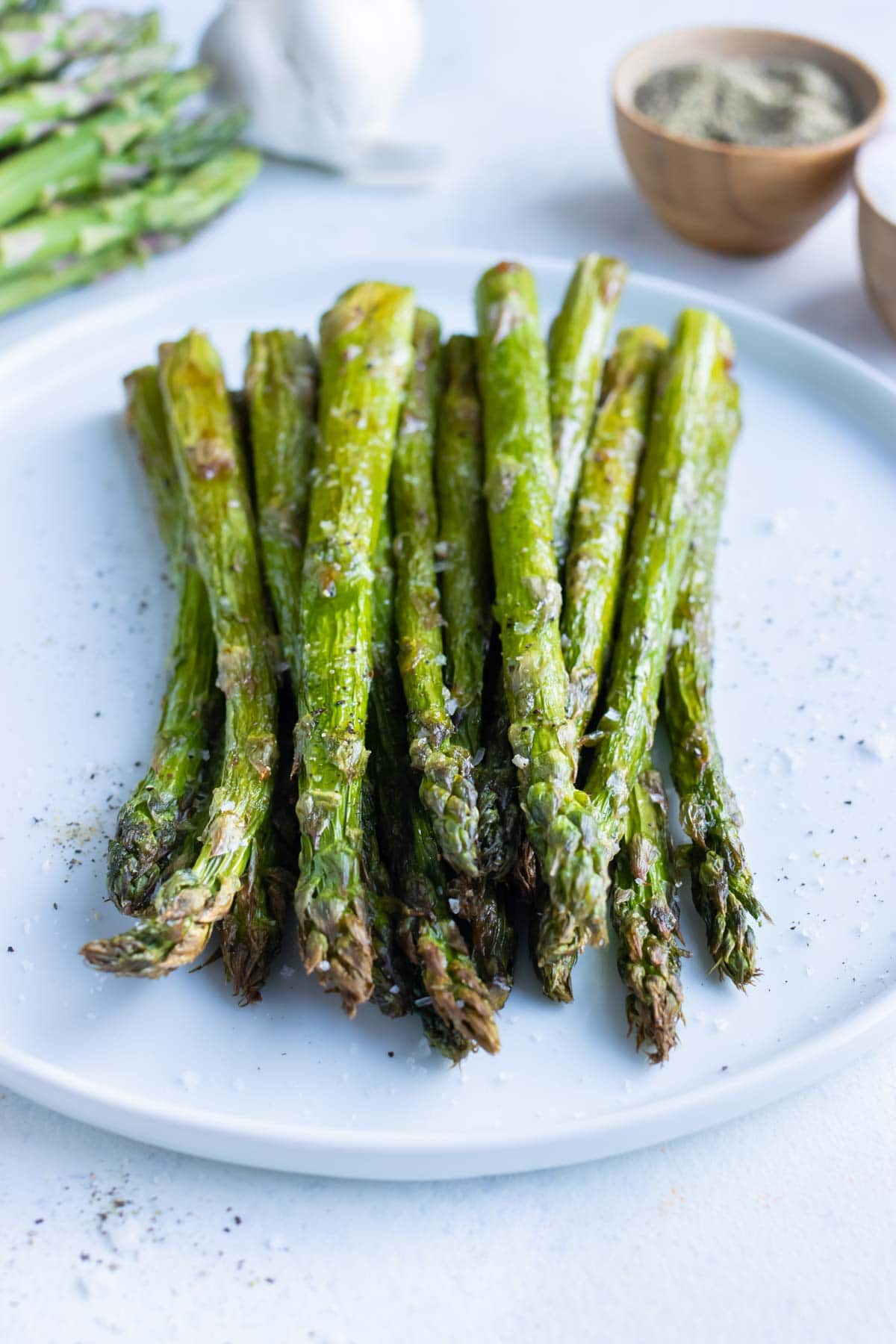 Low-carb air fryer asparagus is dished on a white plate.
