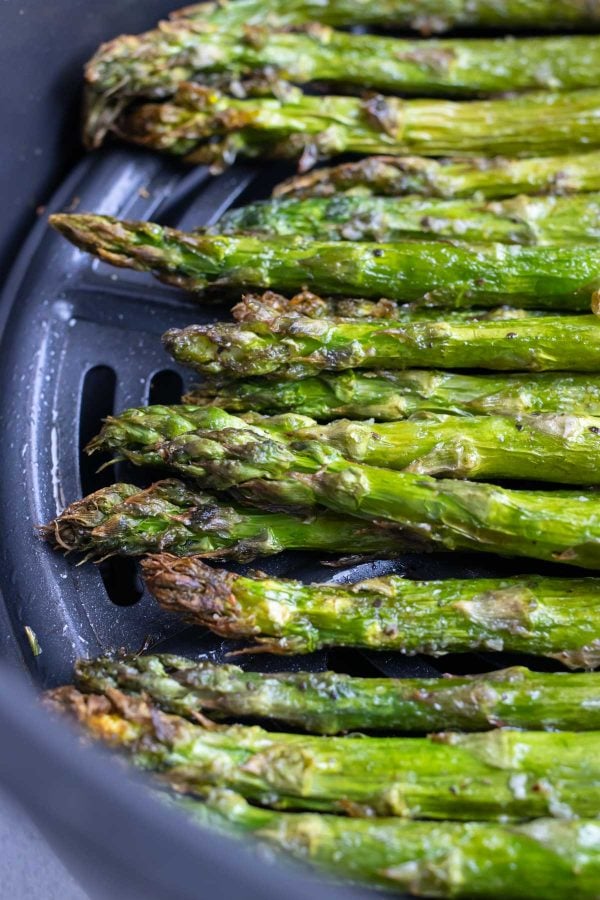 Crispy asparagus in the basket of an air fryer.