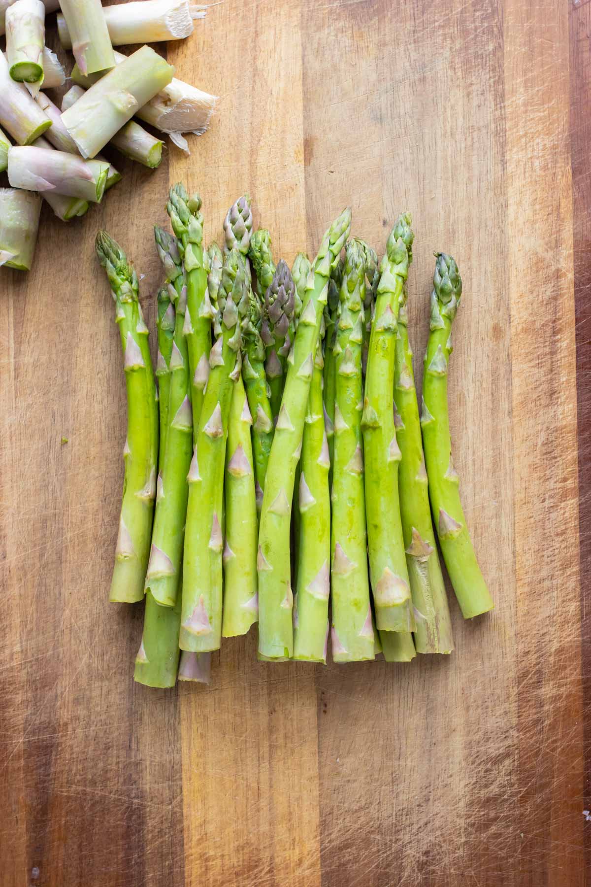 Raw asparagus is set on a cutting board.