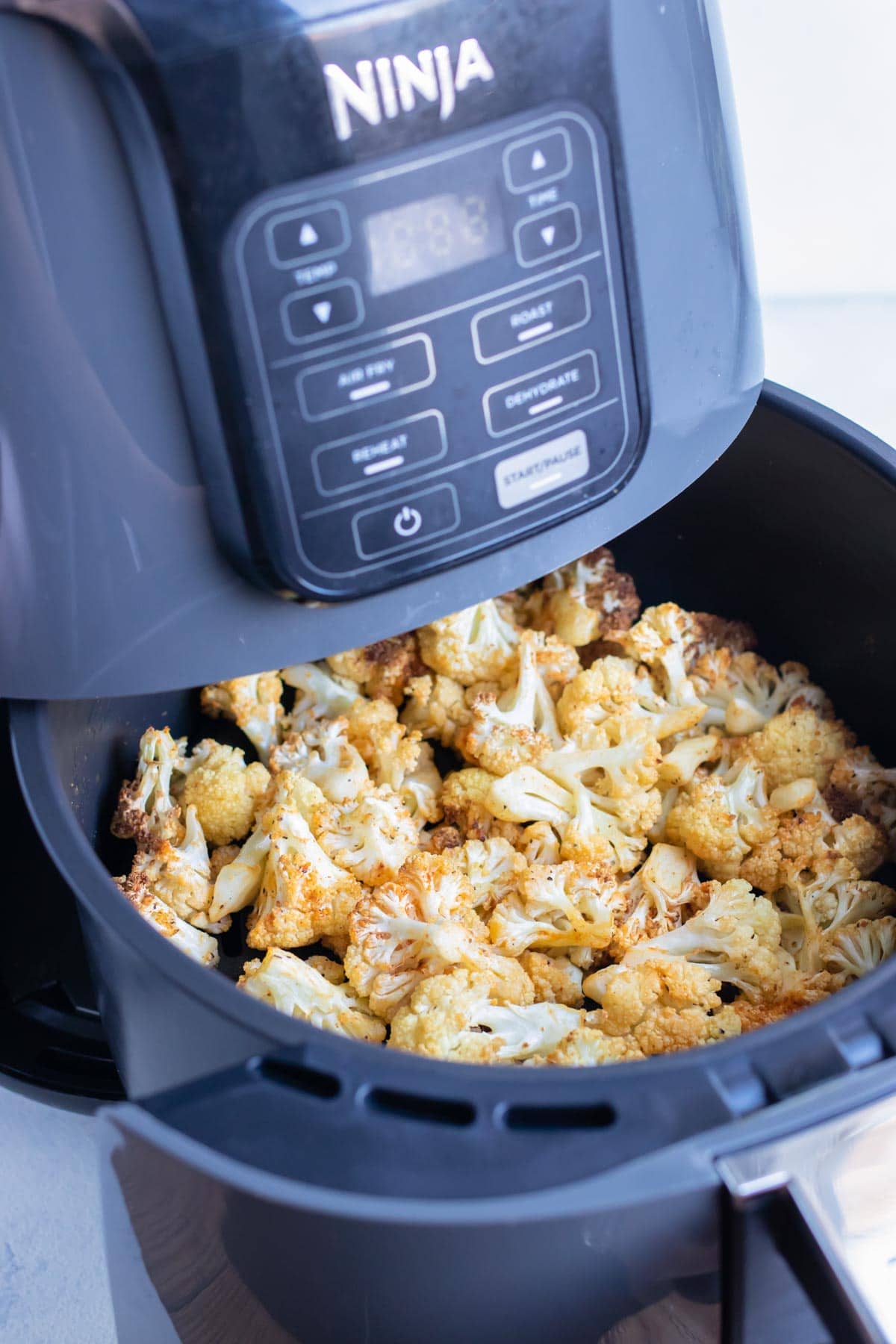 An air fryer holds crispy, seasoned cauliflower.