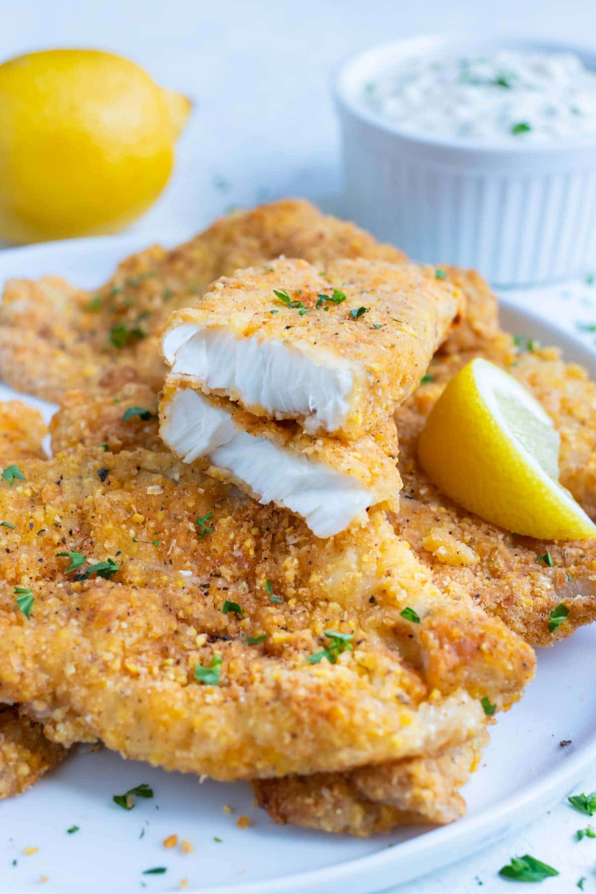 Breaded fish is served on a white plate.