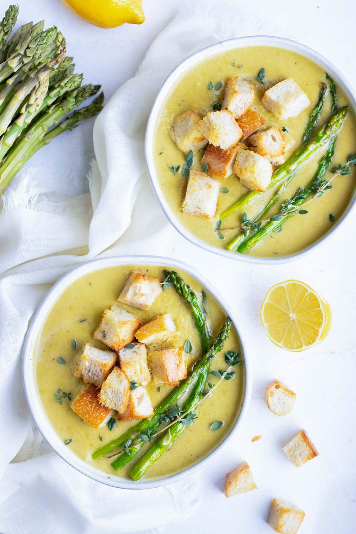 Two soup bowl full of a healthy and dairy-free creamy asparagus soup recipe with fresh lemon juice.