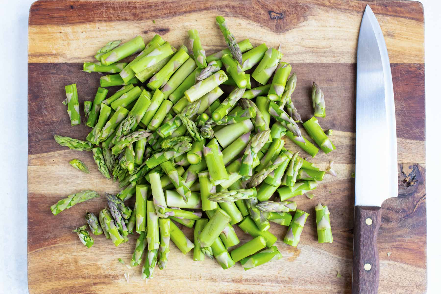 Chopped asparagus on a wooden cutting board.