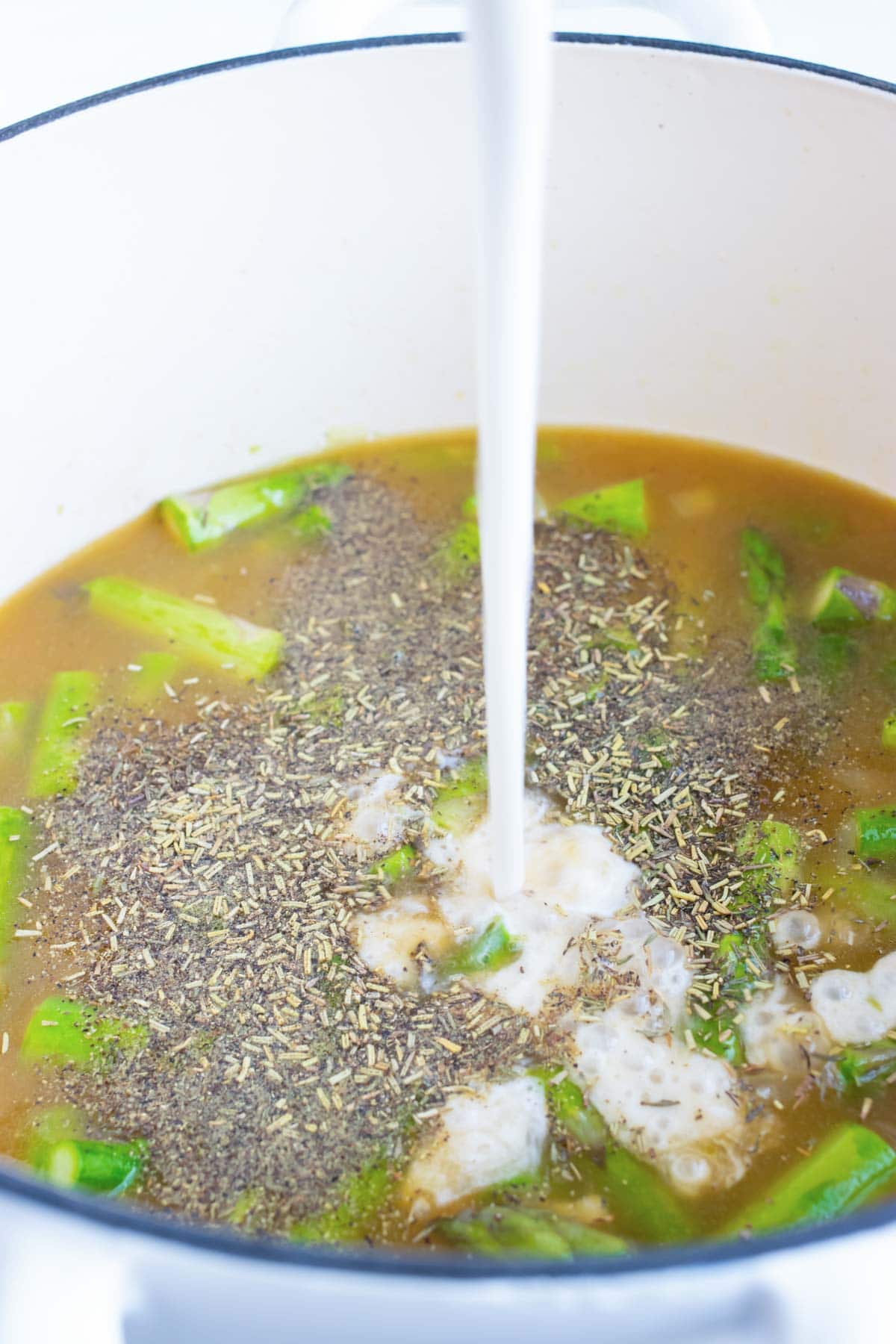 Milk being poured into a pot of soup.