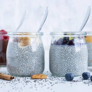 Chia seed pudding is shown in glass jars with spoons.