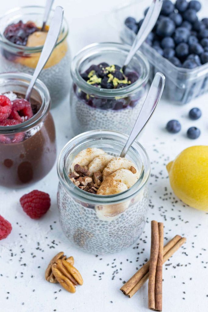 Mason jars of chia seed pudding are shown on the counter in different flavors.