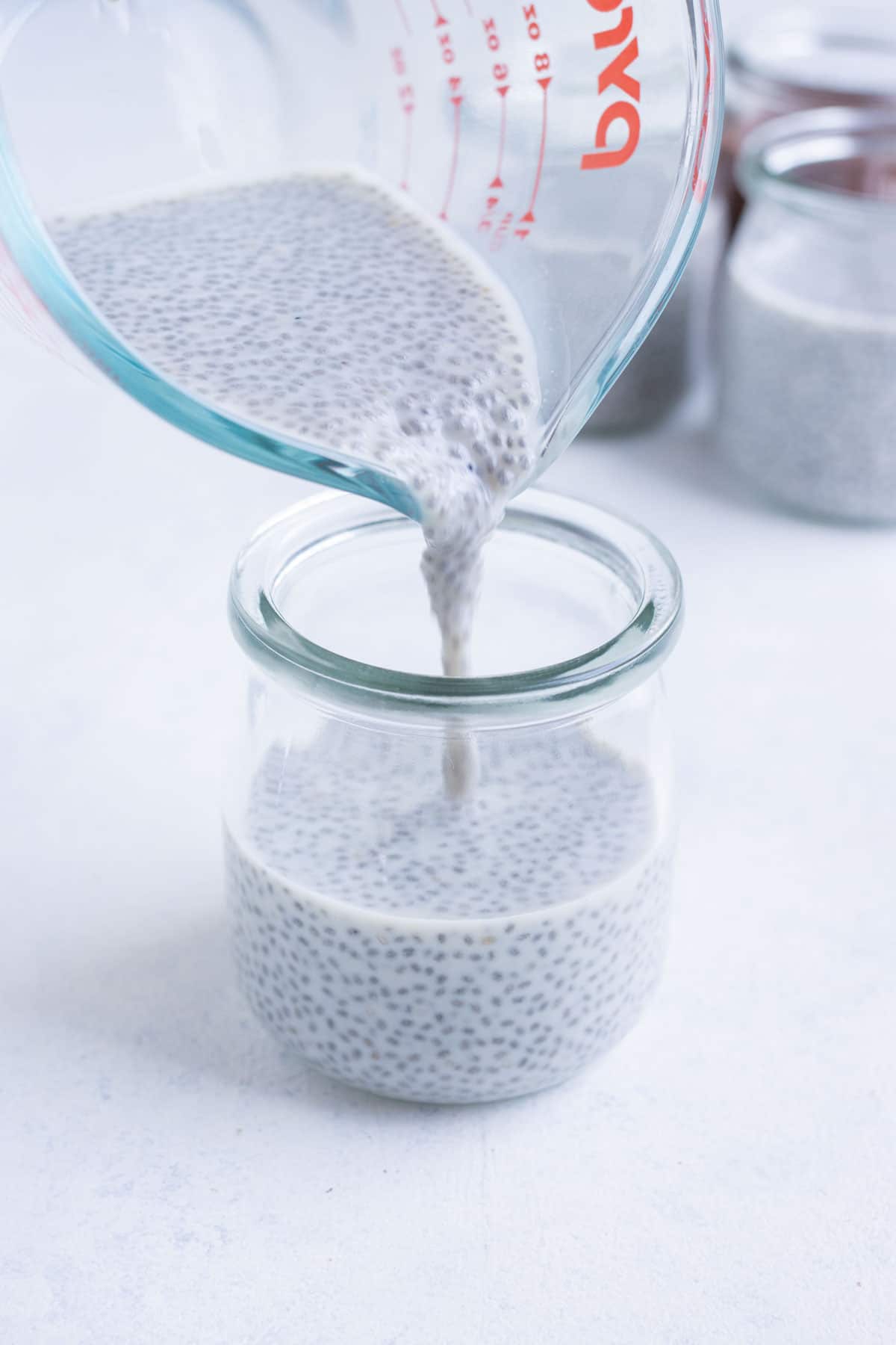 The chia seed pudding mixture is poured into 4 small mason jars.