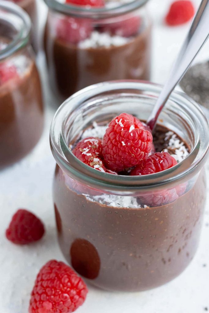 Raspberries are put on top of chocolate chia seed pudding.