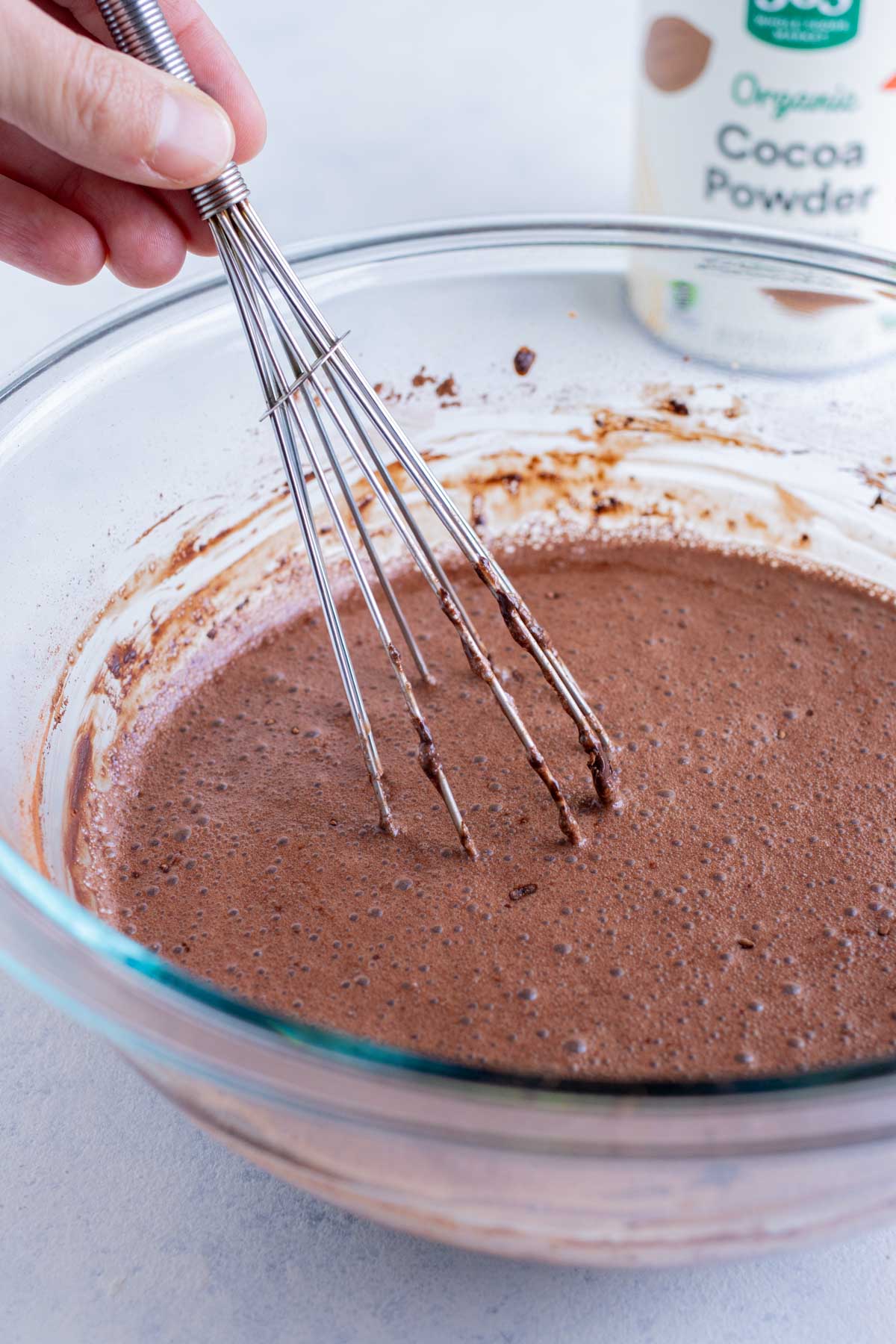 Cocoa powder, sweetener, vanilla, and milk are mixed together in a bowl.