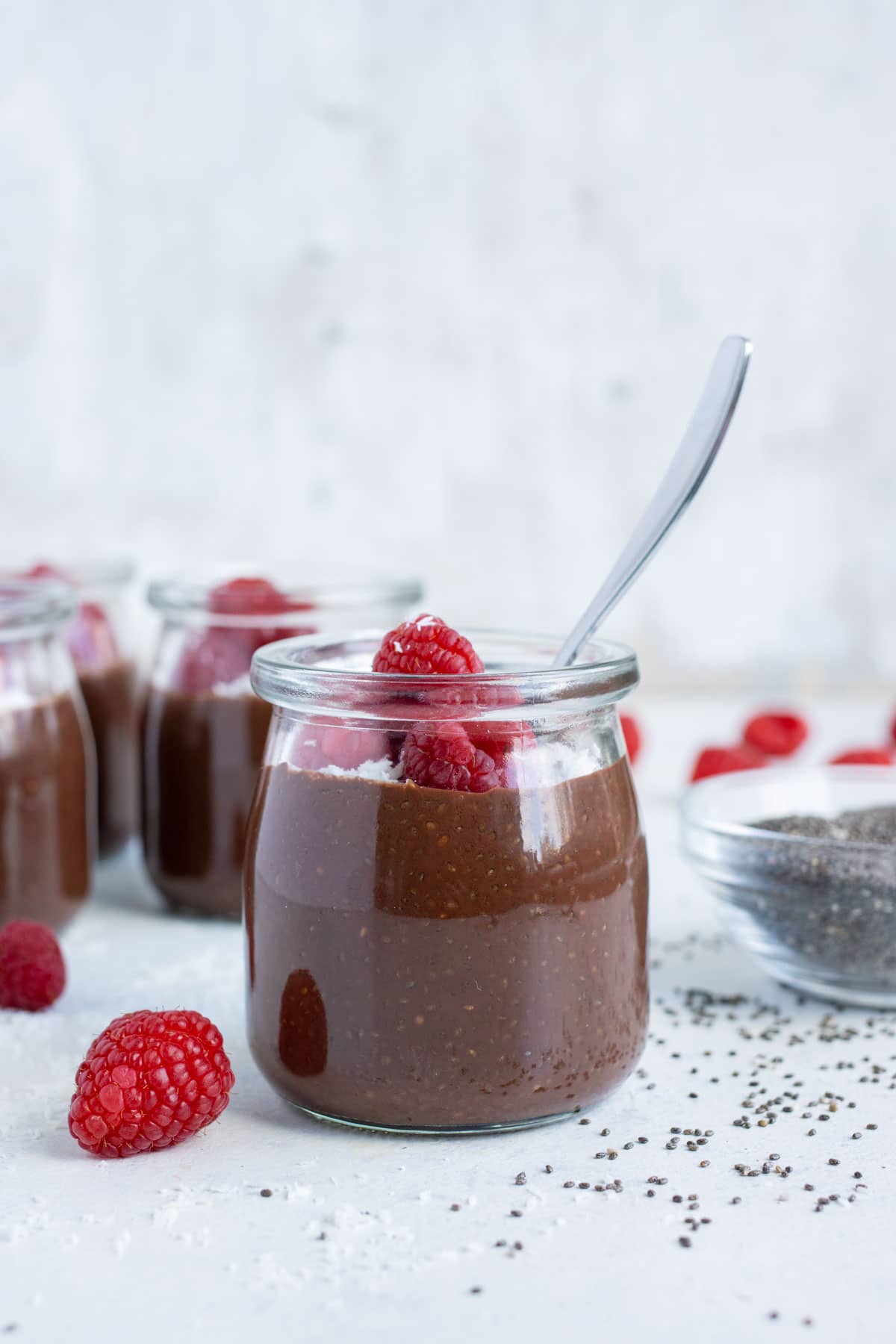 Multiple jars of chocolate chia seed pudding are shown on the counter.