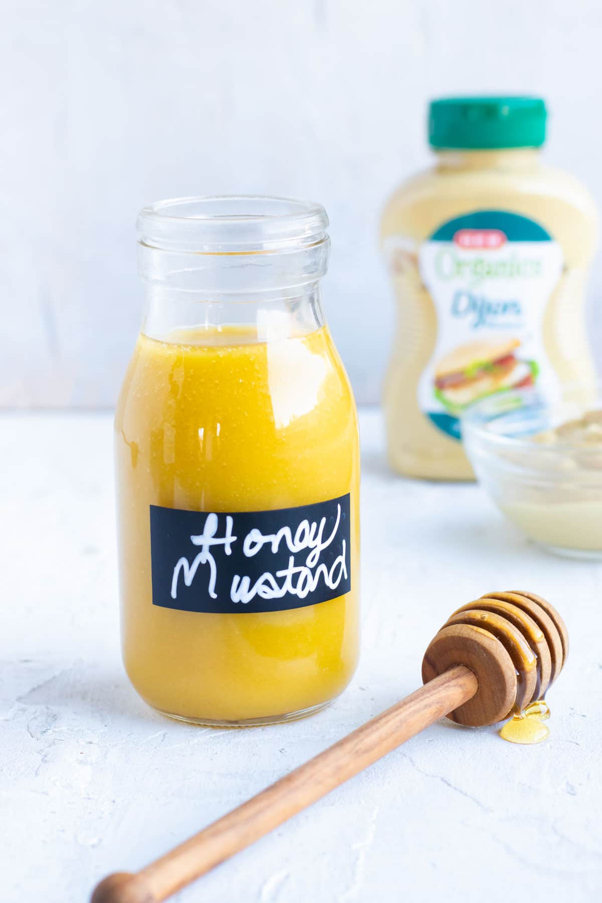 Honey mustard salad dressing recipe in a glass jar with a jar of Dijon mustard.