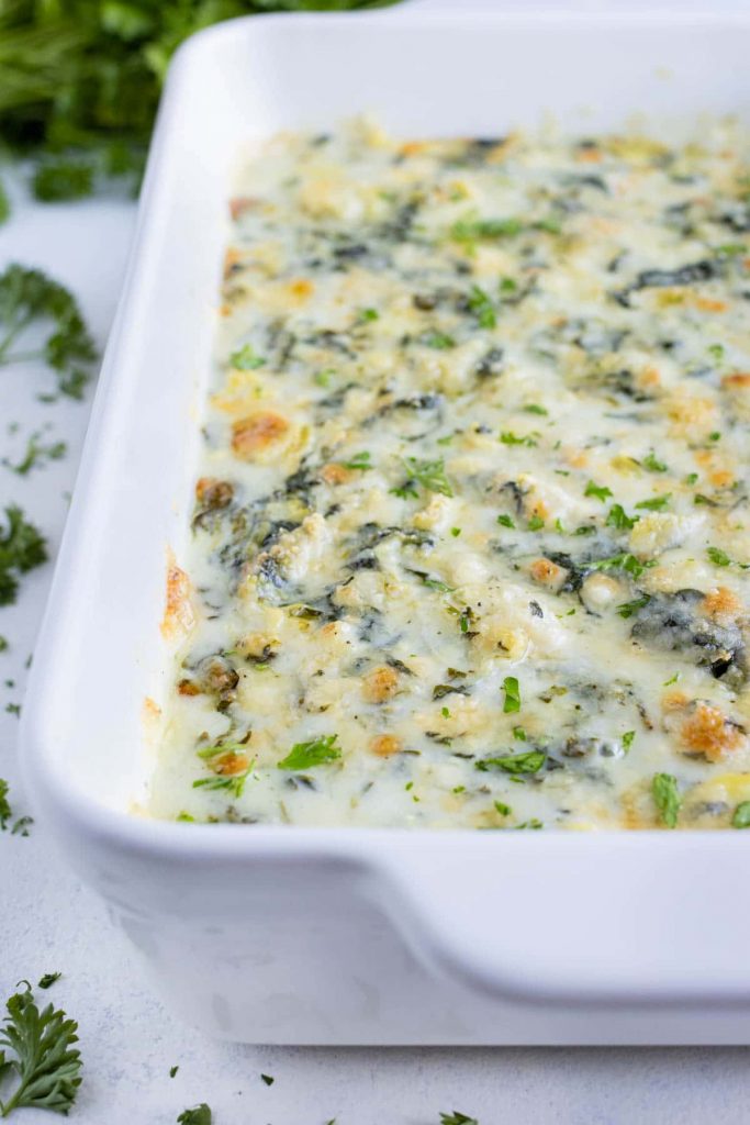 Hot spinach artichoke dip is served from a baking dish.