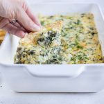 Hot spinach dip is eaten with a tortilla chip.