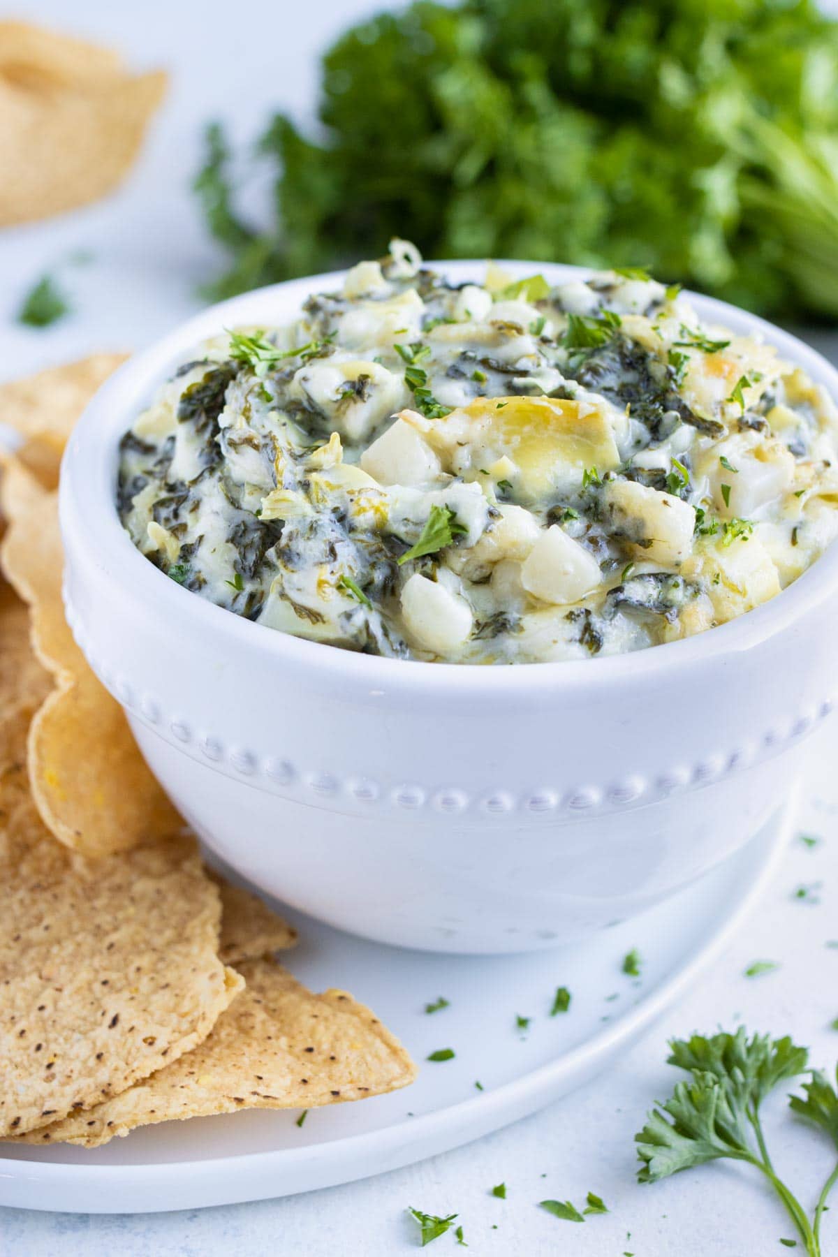 Creamy spinach artichoke dip is served with tortilla chips from a bowl.