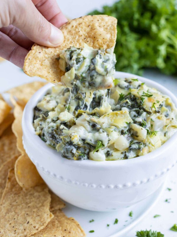 A chip is loaded with hot spinach artichoke dip for an appetizer.