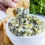 Cheesy spinach artichoke dip is shown in a bowl