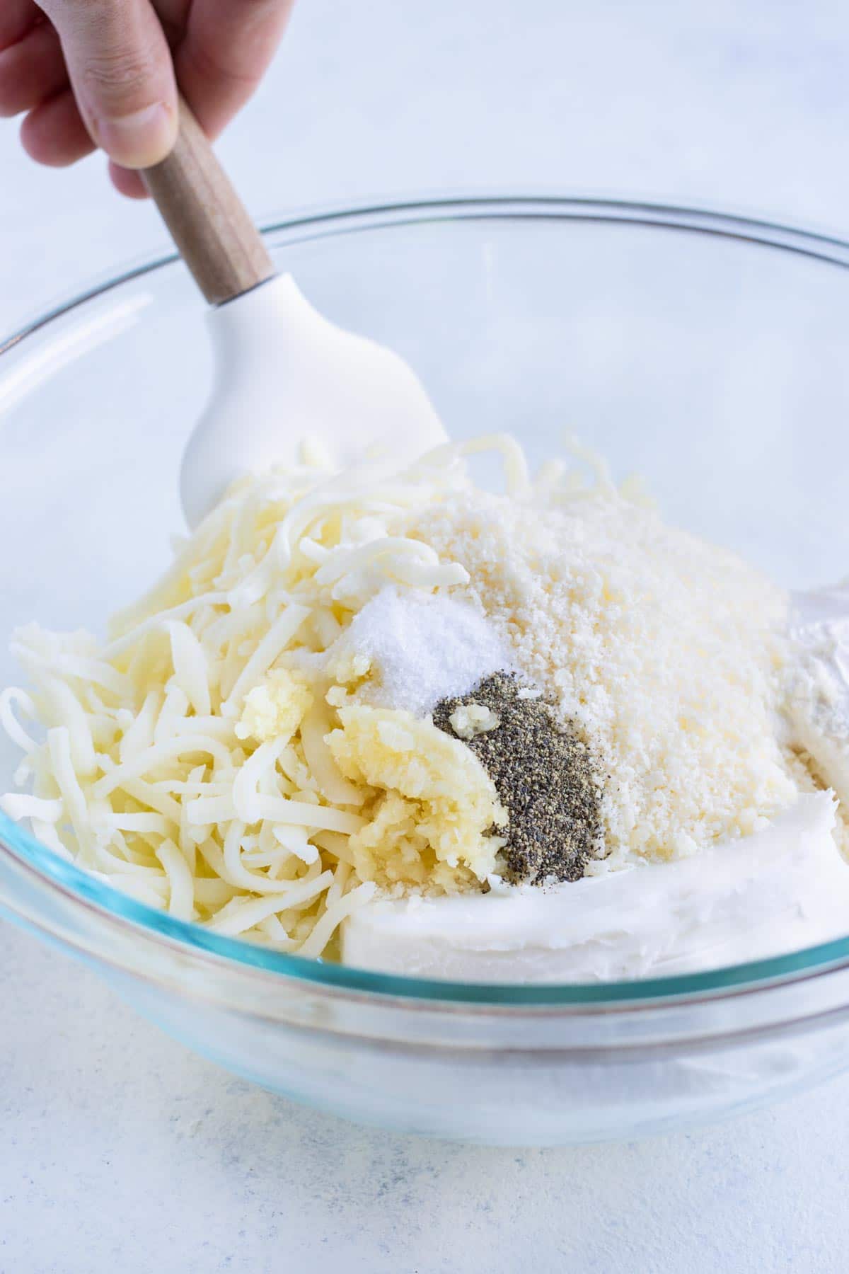 Cream cheese, mozzarella, parmesan, sour cream, and seasonings are mixed together.