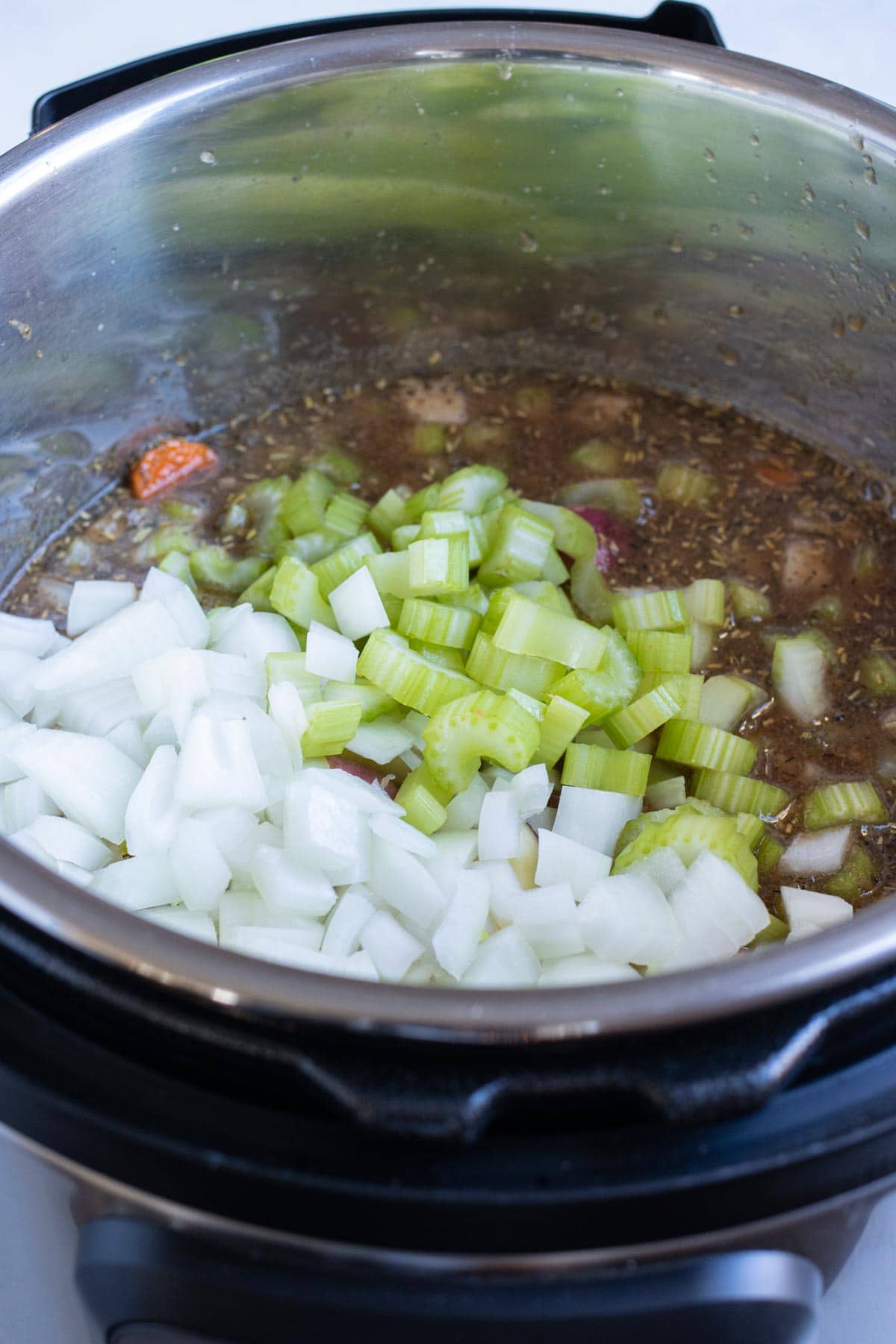 Diced vegetables are added to the pressure cooker.