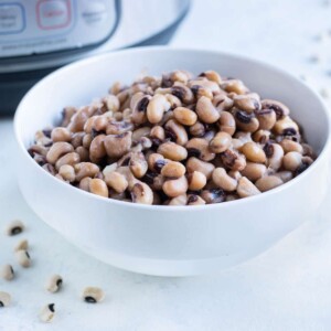 A white bowl is full of black eyed peas.
