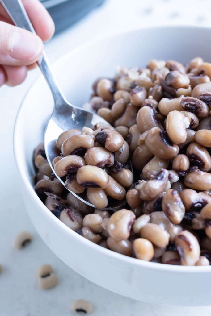A spoon is used to dish black eyed peas.