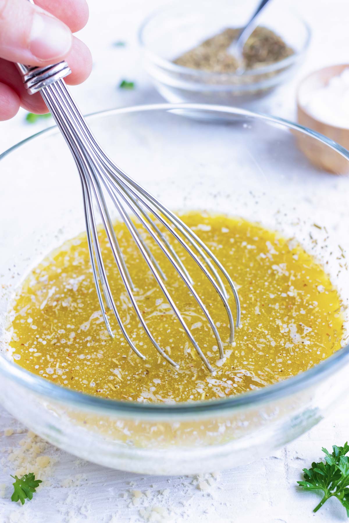 A glass bowl with homemade Italian dressing being whisked together.