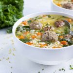 Comforting Italian wedding soup is served in a white bowl.