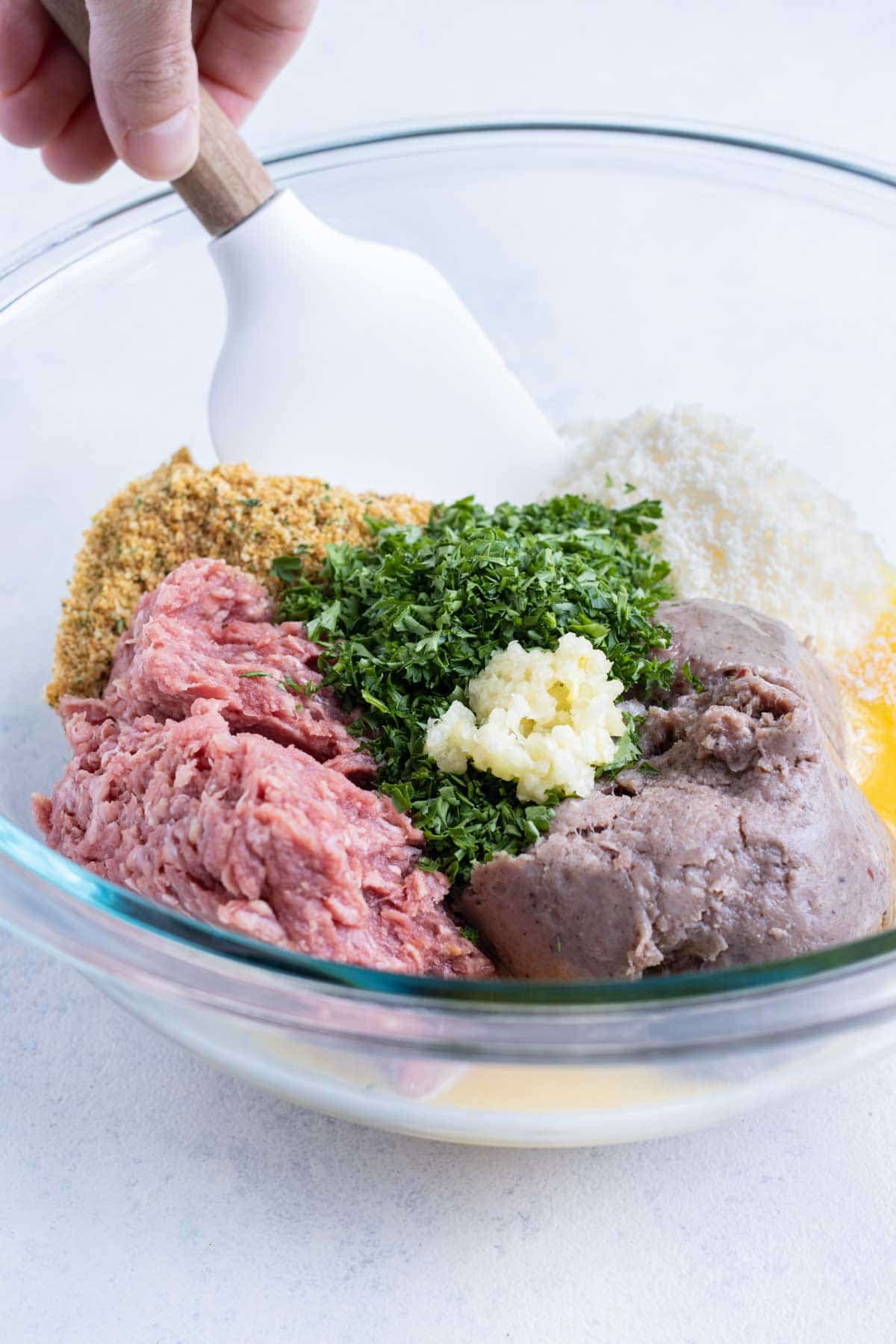 Meatball ingredients are measured out into a bowl.