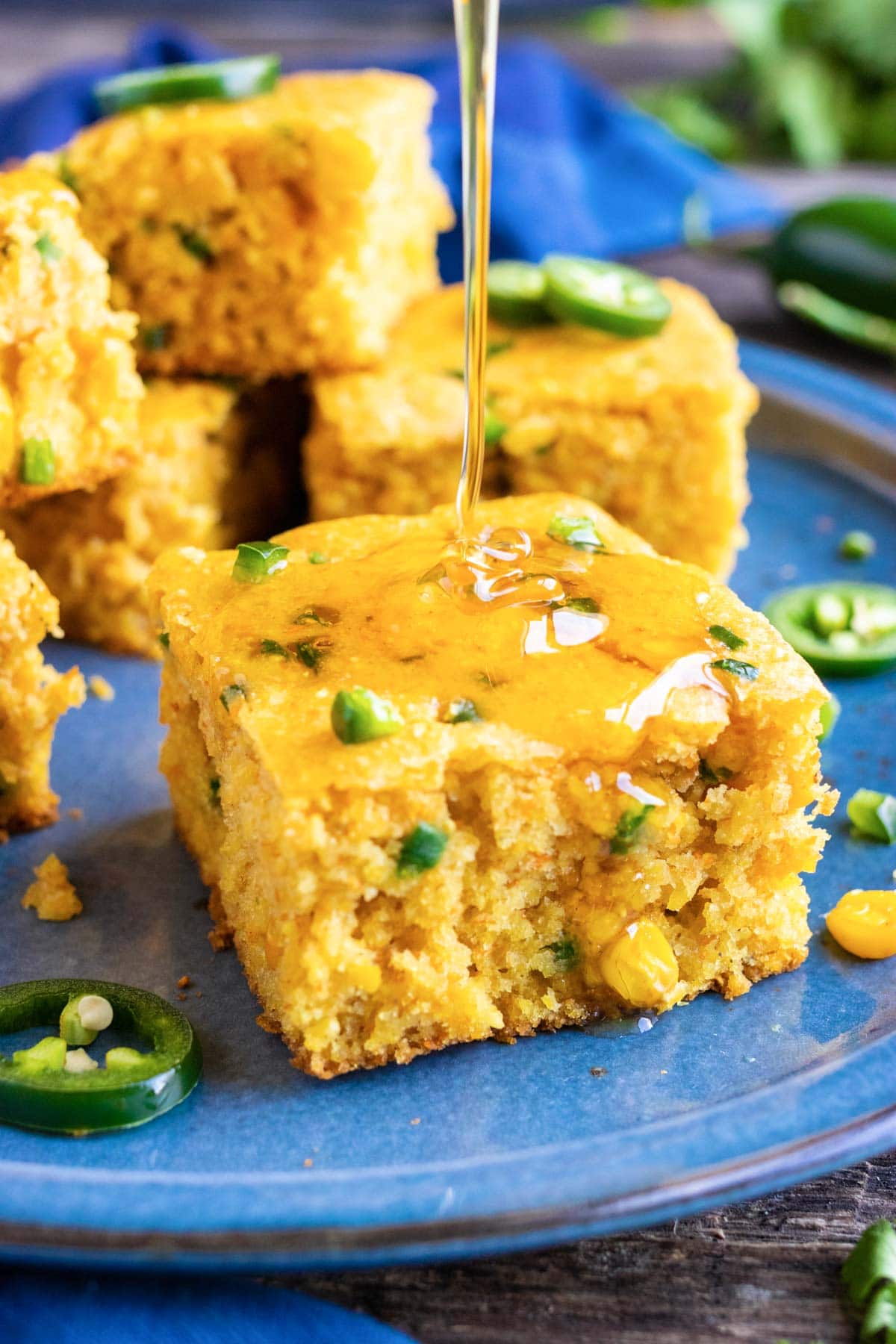 A drizzle of honey being poured on a piece of jalapeño cornbread.