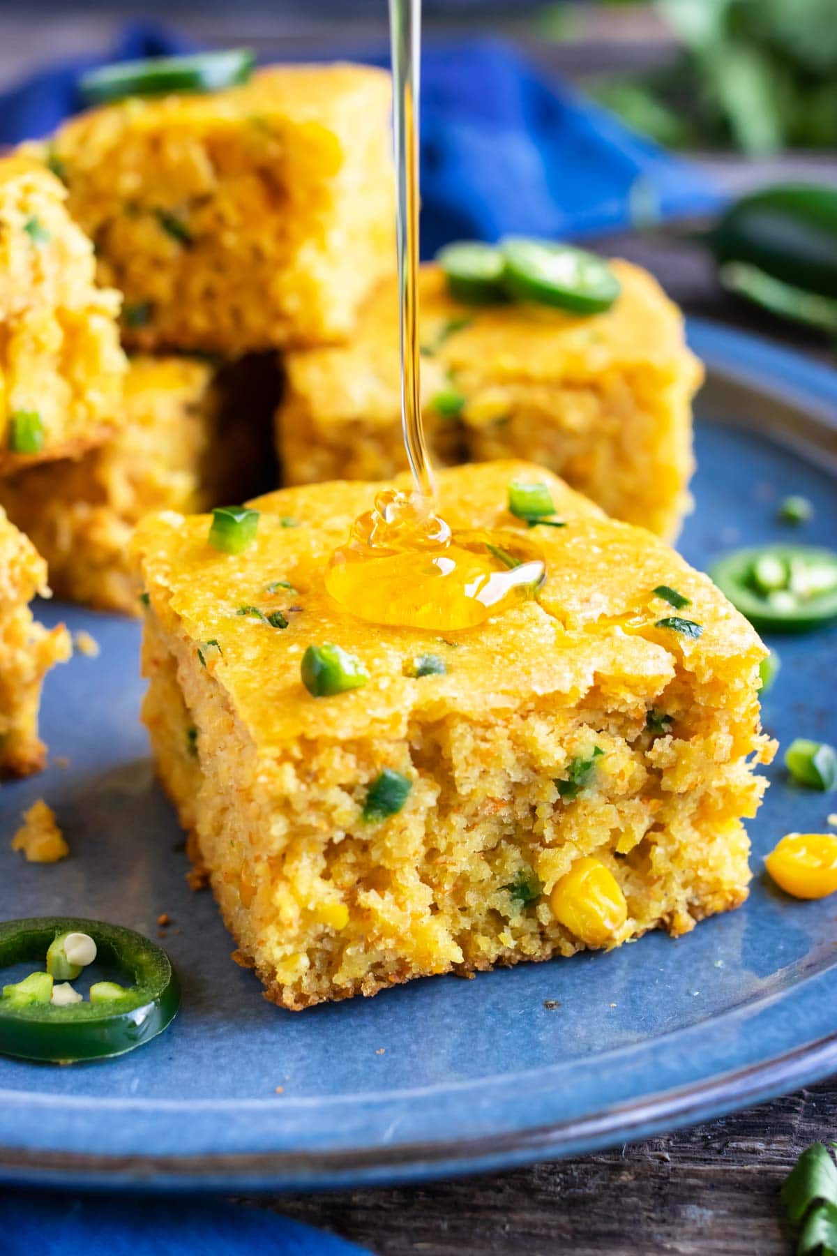 A drizzle of honey being poured on a piece of jalapeño cornbread.