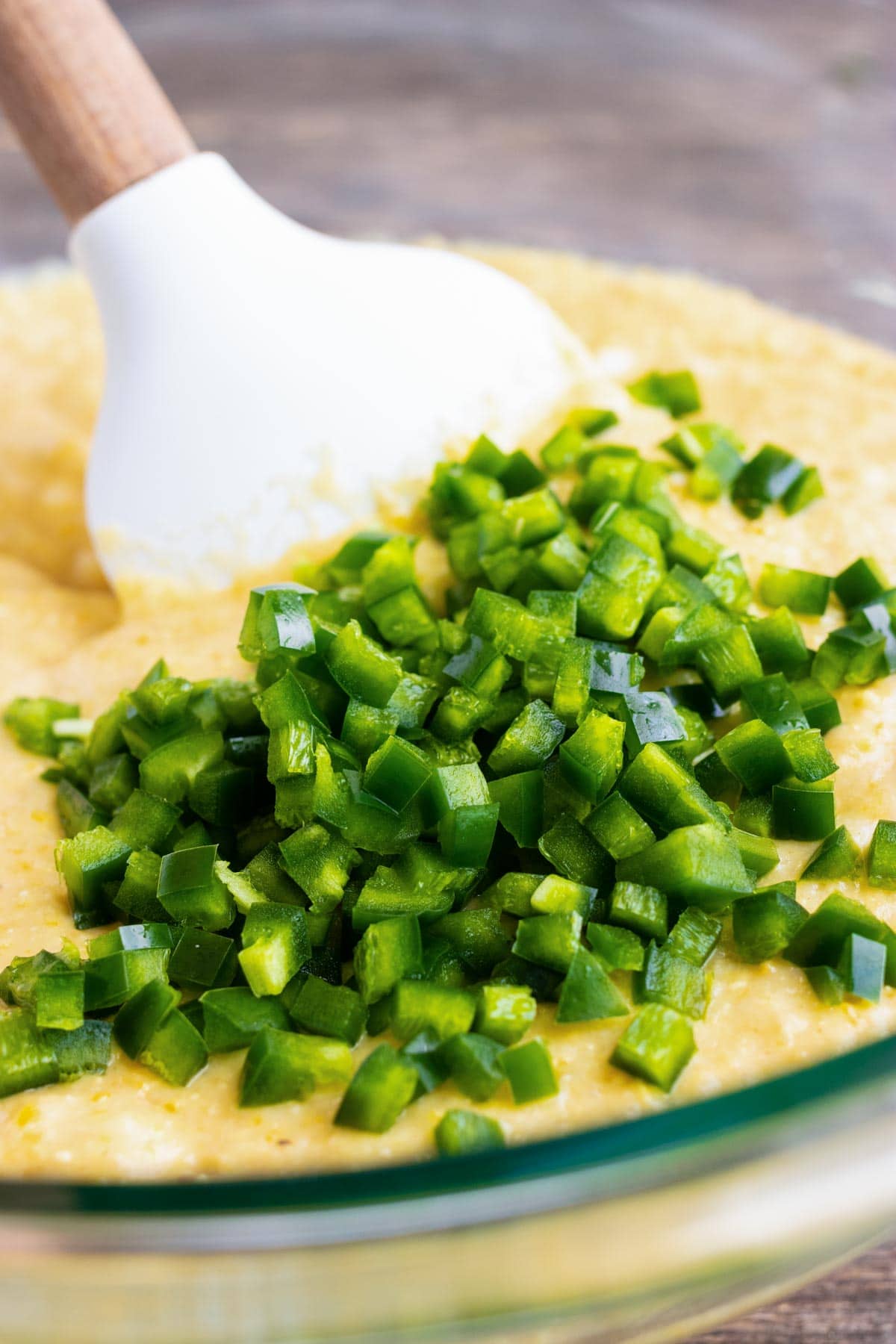 Jalapeños being added to a cornmeal batter before baking.