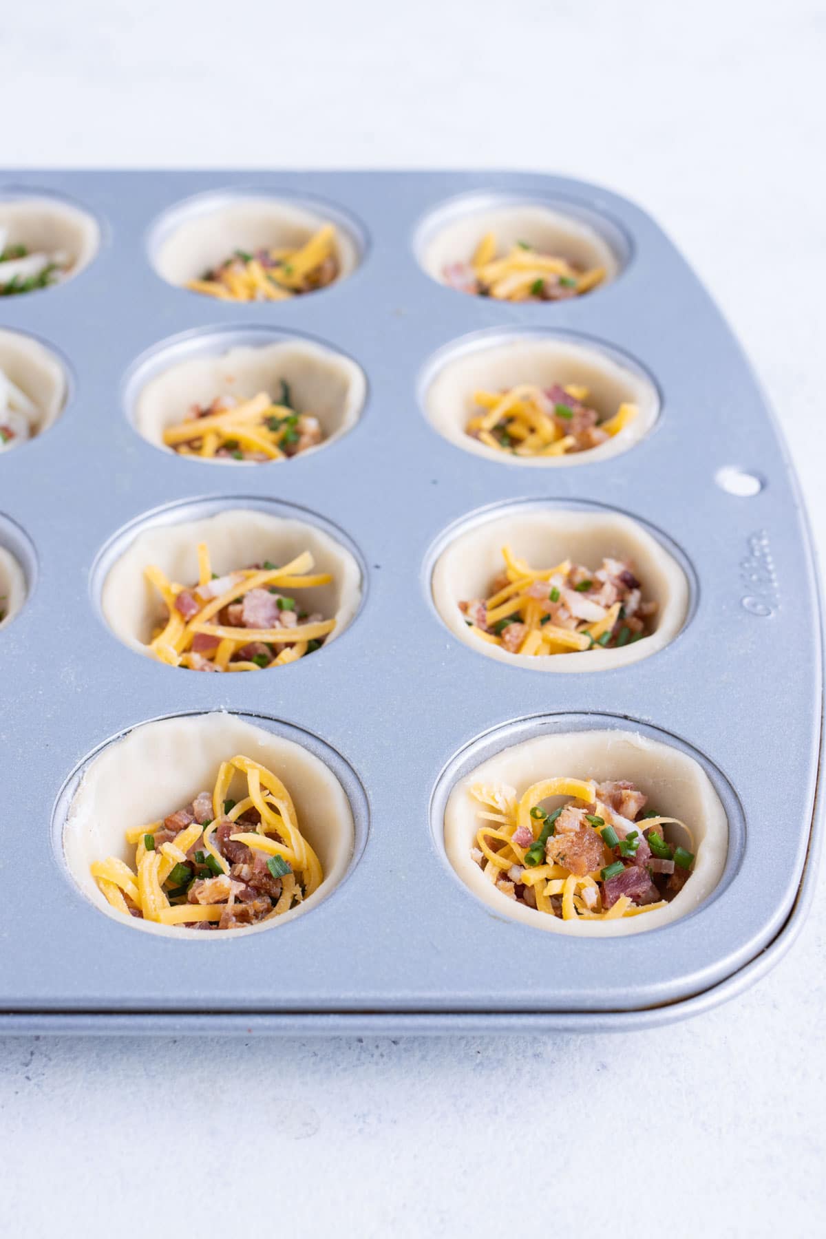 Cheese is added to the mini quiches.