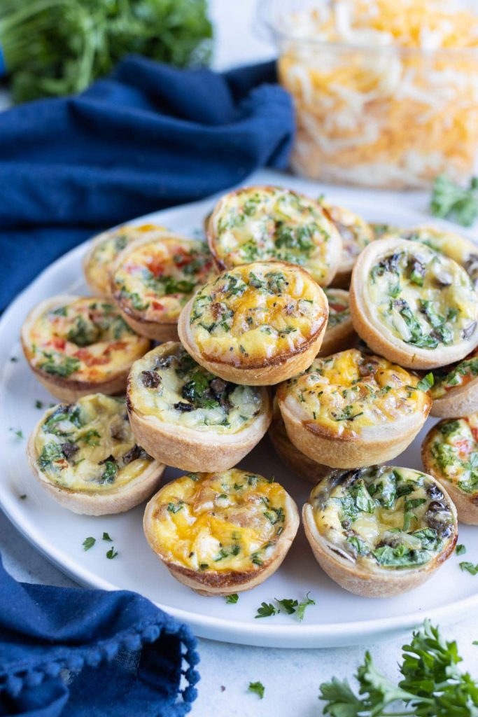 Mini quiches are stacked on a plate for a holiday appetizer.