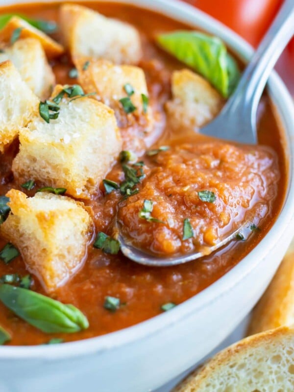 A spoon scooping out a bite of a thick and creamy roasted tomato soup recipe.